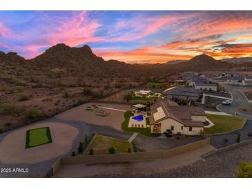 Expansive property featuring a pool, sport court, putting green, and mountain views at sunset at 297 W Chase St, San Tan Valley, AZ 85143