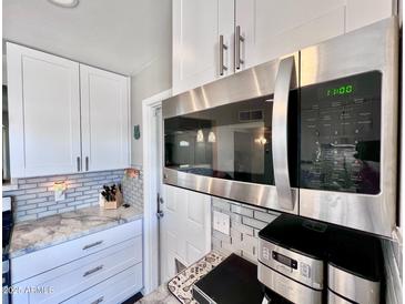 Well-lit kitchen featuring white cabinets, stainless steel microwave, and stylish countertops at 3328 W Charter Oak Rd, Phoenix, AZ 85029