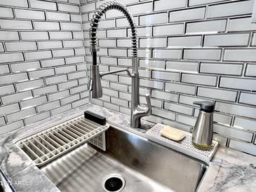 Close-up of a kitchen sink featuring stylish fixtures and subway tile backsplash at 3328 W Charter Oak Rd, Phoenix, AZ 85029