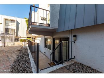 Condo exterior featuring a small balcony and basement-level doorway entrance and black metal banisters at 3416 N 44Th St # 70, Phoenix, AZ 85018