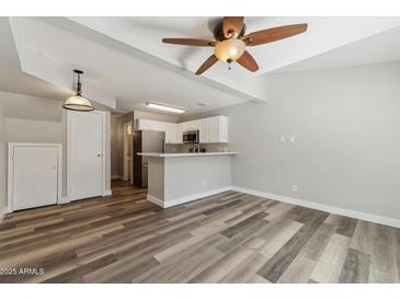 Open-concept living space featuring modern wood-look floors and a ceiling fan flowing into the kitchen at 510 N Alma School Rd # 103, Mesa, AZ 85201