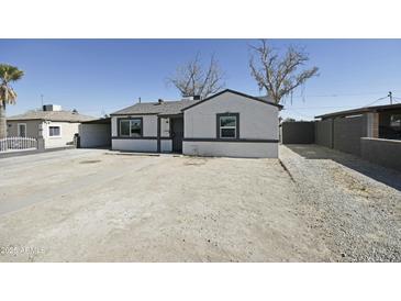 Charming single-story home featuring a low-pitched roof, white stucco, dark trim and a large front yard at 6029 S 6Th Ave, Phoenix, AZ 85041