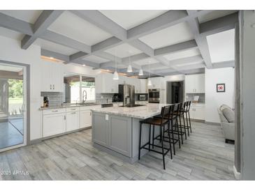 Spacious kitchen featuring a large island with seating, white cabinets, and modern stainless steel appliances at 2106 W Shawnee Dr, Chandler, AZ 85224