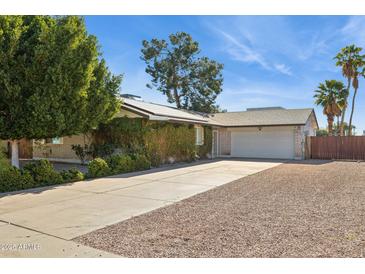 Charming single-story home featuring an attached garage, lush landscaping and mature trees at 2935 W Dailey St, Phoenix, AZ 85053