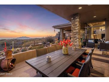 Beautiful covered patio area showcasing an outdoor dining table with mountain views at sunset at 38951 N 101St Way, Scottsdale, AZ 85262