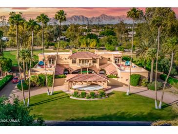 Stunning estate featuring lush landscaping, circular drive, and a resort-style backyard with mountain views at 7155 E Oakmont Dr, Paradise Valley, AZ 85253