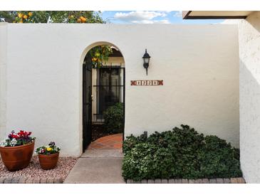 Inviting gated entry featuring an arched gate and colorful potted plants at 1221 E Palacio Dr, Phoenix, AZ 85014