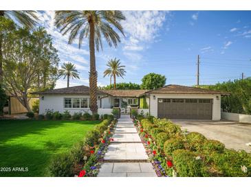 Charming home featuring a landscaped front yard, a white exterior, and a welcoming stone pathway and mature palm trees at 4701 E Calle Redonda St, Phoenix, AZ 85018