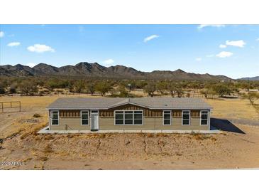 Charming single-story home with neutral siding and many windows showcasing natural light with a mountain backdrop at 53573 W Fresno Rd, Maricopa, AZ 85139