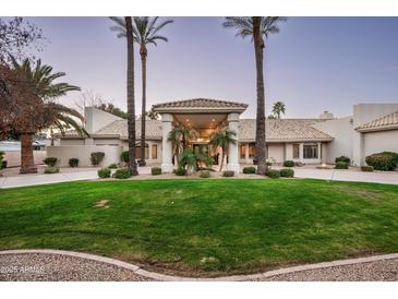 Elegant home featuring manicured lawn, palm trees, and a circular driveway leading to a covered entrance at 9128 N 70Th St, Paradise Valley, AZ 85253