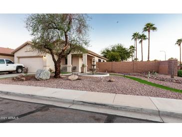 Charming single-story home featuring a well-manicured yard, mature trees, desert landscaping, and a unique water fountain at 11197 W Coronado Rd, Avondale, AZ 85392