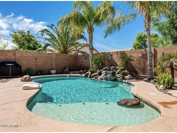 Backyard pool featuring a rock waterfall, palm trees, and a pristine pool area at 18626 N 28Th Way, Phoenix, AZ 85050