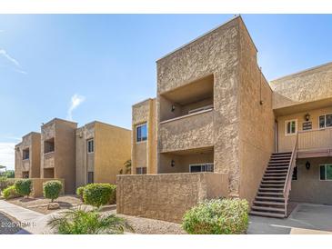 Condominium exterior featuring stucco finish, stairs, and a private balcony with outdoor seating at 5877 N Granite Reef Rd # 2203, Scottsdale, AZ 85250