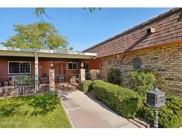 Charming home featuring a cozy front porch with decorative iron railings and manicured landscaping at 9802 W Shasta Dr, Sun City, AZ 85351