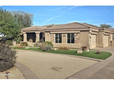 Stunning single-story home with stone accents, lush landscaping, and a circular driveway at 10236 W Westwind Dr, Peoria, AZ 85383