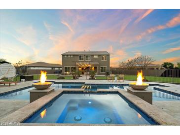 Stunning pool and spa with fire bowls and beautiful backyard at dusk at 1180 E Ibis St, Gilbert, AZ 85297