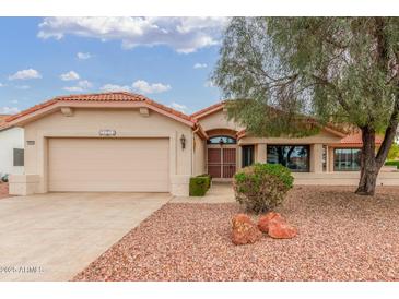 Charming home with a well-maintained front yard featuring mature landscaping, a two-car garage, and inviting curb appeal at 20603 N Stonegate Dr, Sun City West, AZ 85375