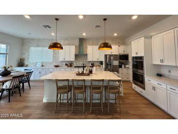 Spacious kitchen featuring an island, white cabinets, stainless steel appliances, and modern pendant lighting at 22703 E Alyssa Rd, Queen Creek, AZ 85142