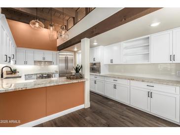 Bright kitchen with white cabinets, stone countertops, stainless steel appliances, and unique light fixtures at 8502 E Cave Creek Rd # 53, Carefree, AZ 85377