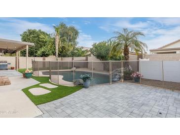 Backyard features pool with waterfall, patio, and lush landscaping at 9001 W Lone Cactus Dr, Peoria, AZ 85382