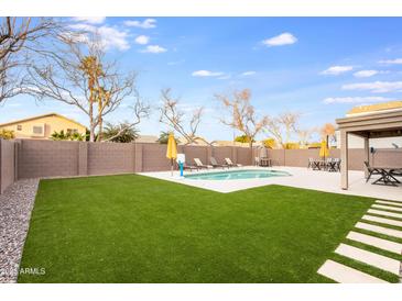 A backyard with a pool, artificial turf, and a covered patio provides space for outdoor relaxation and entertainment at 9144 W Quail Ave, Peoria, AZ 85382