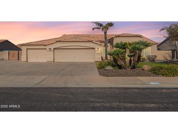 Charming single-story home featuring a three-car garage, desert landscaping, and a clay tile roof at sunset at 9544 E Irwin Ave, Mesa, AZ 85209