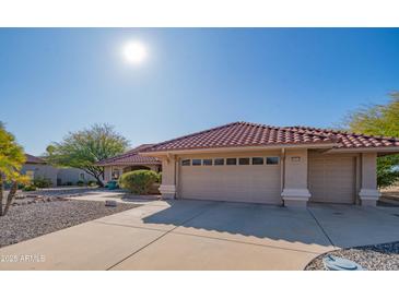 Charming home featuring a red tile roof, a two-car garage, and mature landscaping at 13913 W Whitewood Dr, Sun City West, AZ 85375