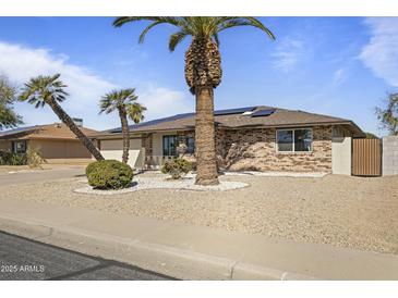 Charming single-story brick home featuring mature palm trees and low-maintenance desert landscaping at 17410 N Conquistador Dr, Sun City West, AZ 85375