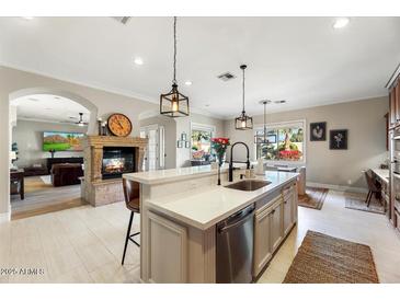 Elegant kitchen featuring an island with a sink, pendant lighting, and an adjoining dining area at 6960 E Ivyglen St, Mesa, AZ 85207