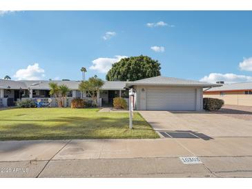 Charming single-story home featuring a well-manicured lawn and a two-car garage at 10303 W Desert Forest N Cir, Sun City, AZ 85351