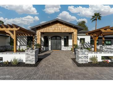 Stunning home entrance with a striking wooden gable and an inviting brick pathway to the custom double doors at 7014 E Palo Verde Ln, Paradise Valley, AZ 85253
