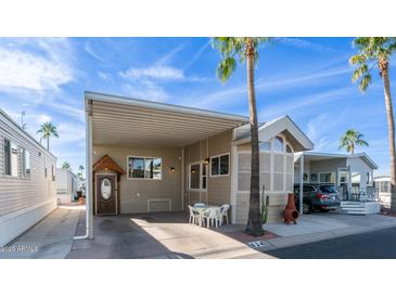 Charming home featuring covered parking, a cozy seating area, and lush palm trees against a bright blue sky at 834/837 S Beryl/Aquamarine Dr, Apache Junction, AZ 85119