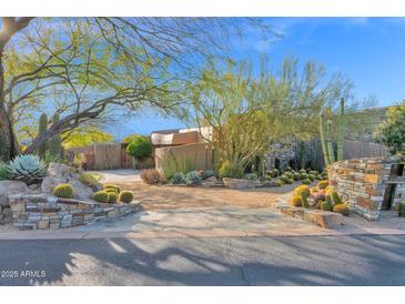 A desert landscape welcomes you to this home with mature trees, cacti, and stone accents, with a circular driveway at 34460 N 79Th Way, Scottsdale, AZ 85266