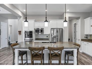 Modern kitchen with white cabinets, granite countertops, stainless steel appliances, and three pendant lights at 3930 E Enrose St, Mesa, AZ 85205