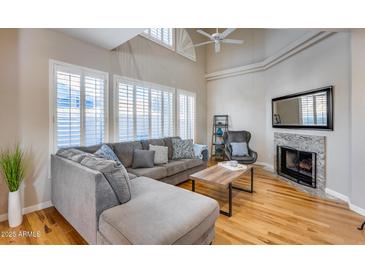 Bright living room featuring a gray couch, fireplace, and large windows with white shutters at 10203 N 12Th Pl # 3, Phoenix, AZ 85020