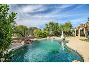 Beautiful backyard pool with rock waterfall feature and lush landscaping in a private setting at 15109 W Camino Estrella Dr, Surprise, AZ 85374