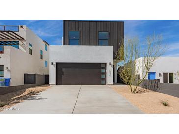 Striking modern home with a dark garage door, complemented by desert landscaping and unique architectural details at 4514 N 8Th Pl, Phoenix, AZ 85014