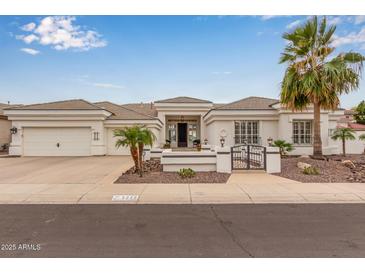 Stunning white home featuring a well-kept landscape, tile roof, three car garage, and a decorative front gate at 5323 W Rose Garden Ln, Glendale, AZ 85308