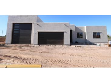 Modern home exterior featuring a stucco facade, dark garage doors, and desert landscaping at 29022 N 166Th Ave, Surprise, AZ 85387