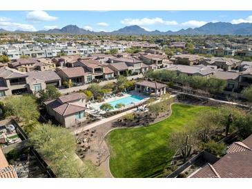 Stunning aerial view of the community pool, green space, and surrounding homes, all with a mountain view in the background at 7340 E Conquistadores Dr, Scottsdale, AZ 85255