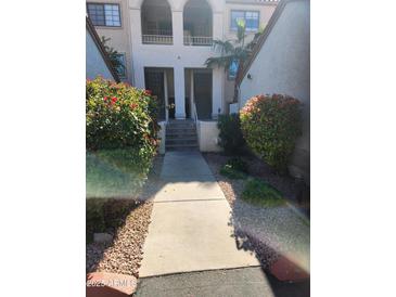 Inviting condo exterior with well maintained walkway, beautiful flowering bushes, and covered entrances at 10080 E Mountainview Lake Dr # 110, Scottsdale, AZ 85258