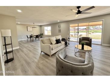 Open-concept living room featuring new floors, neutral paint, ample seating, and bright, natural light at 18442 N 104Th Ave, Sun City, AZ 85373