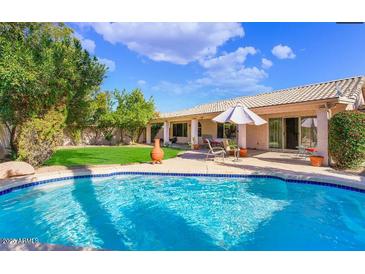 Gorgeous backyard oasis featuring a sparkling pool, lush lawn, and covered patio perfect for outdoor living at 20218 N 61St Ave, Glendale, AZ 85308