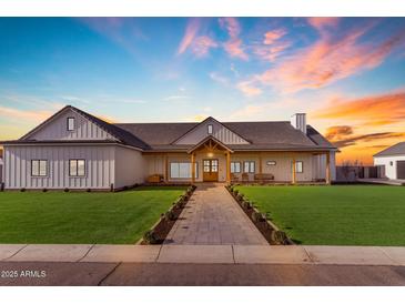 Beautifully designed home with a covered porch, complemented by lush green lawn and colorful sunset at 2312 N Raven --, Mesa, AZ 85207