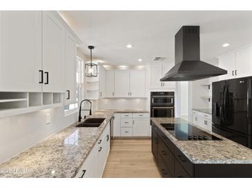 Modern kitchen featuring granite countertops, stainless steel appliances, island cooktop, and white cabinetry at 2366 E Shea Blvd, Phoenix, AZ 85028