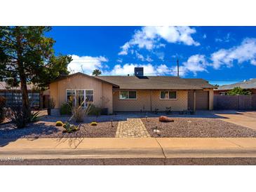 Charming single-story home with a desert landscaped front yard and brick walkway under a blue sky at 8519 E Rancho Vista Dr, Scottsdale, AZ 85251