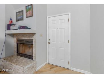 Bright living room with a white door and a cozy fireplace featuring a stone facade and a decorative mantel at 16402 N 31St St # 228, Phoenix, AZ 85032