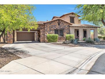 Charming home featuring a stone facade, landscaped front yard, and a spacious driveway leading to a two-car garage at 30227 N 124Th Dr, Peoria, AZ 85383