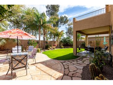 Lush backyard oasis with green grass, palm trees, and a cozy patio area at 32795 N Hidden Canyon Dr, San Tan Valley, AZ 85144
