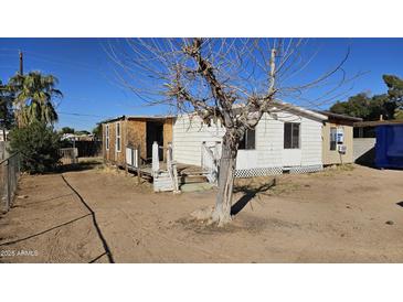 Exterior view of a single-story home with peeling white paint in disrepair and sparse landscaping at 508 S 98Th St, Mesa, AZ 85208